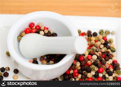 Red Green And Black Peppercorns. Peppercorns in various colors of red, green and the familiar black peppercorn on white with a Mortar and Pestle