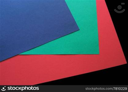 red, green and blue paper on a black background