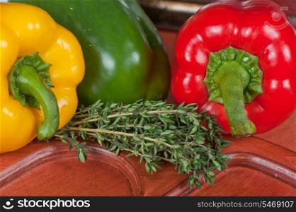Red, green and orange sweet bell peppers and herbs