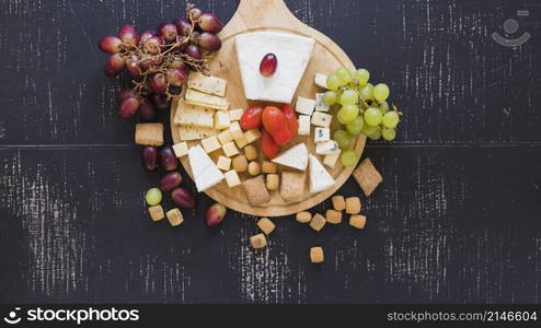 red green grapes tomatoes cheese pastry black textured backdrop