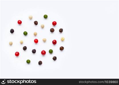 Red, green, white and black peppercorns on white background.. copy space