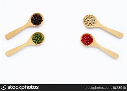 Red, green, white and black peppercorns with wooden spoon on white background.