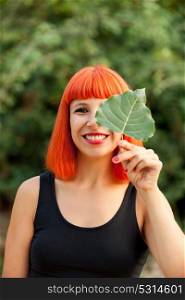 Red hair girl with a tree leaf in a park