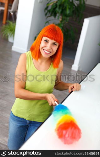 Red hair housewife cleaning her home with a duster