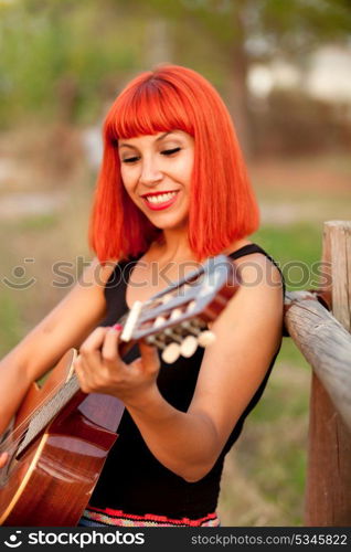 Red hair woman playing guitar in the countryside