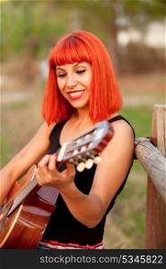 Red hair woman playing guitar in the countryside
