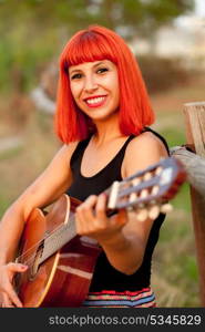 Red hair woman playing guitar in the countryside