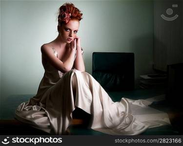 Red haired freckled girl in ivory long dress on secretary table sitting - series of photos