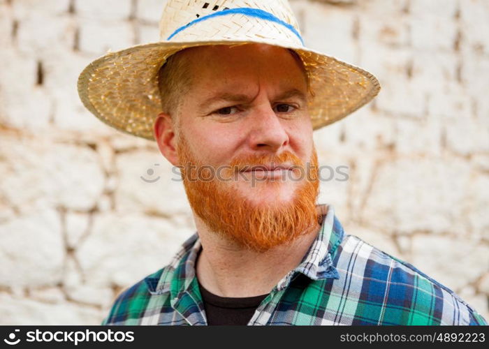 Red haired man with a straw hat in a rural enviroment