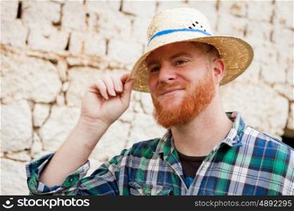 Red haired man with a straw hat in a rural enviroment