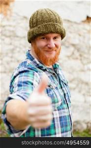 Red haired man with blue plaid shirt and wool hat saying Ok