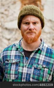 Red haired man with plaid shirt with a old wall with background