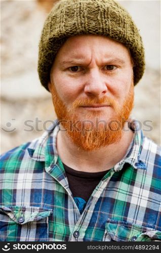 Red haired man with plaid shirt with a old wall with background