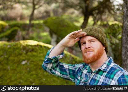 Red haired with beard looks for something in the forest