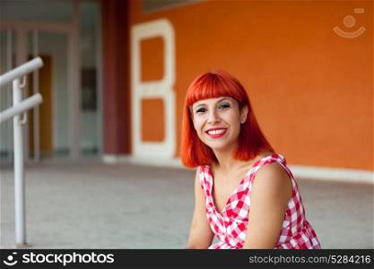 Red haired woman looking at camera in the street with orange background