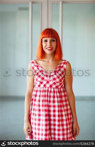 Red haired woman looking at camera with a glass door of background