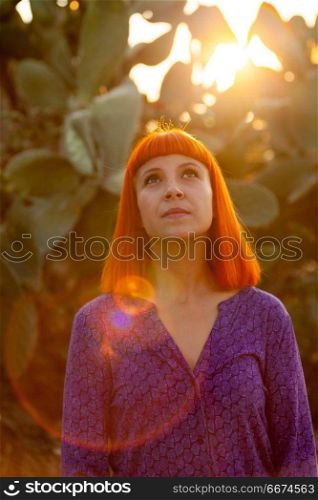 Red haired woman taking a walk. Red haired woman taking a walk by a path during the sunset
