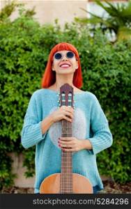 Red haired woman with a guitar in a park enjoying with the music