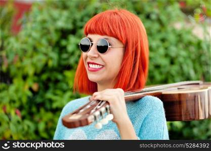 Red haired woman with a guitar in a park enjoying with the music