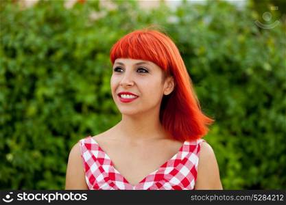Red haired woman with red checkered dress relaxed in a park