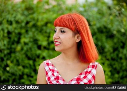 Red haired woman with red checkered dress relaxed in a park