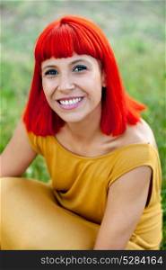 Red haired woman with yellow dress relaxed in a park