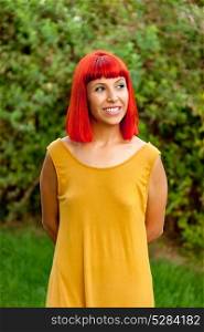 Red haired woman with yellow dress relaxed in a park