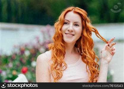 red-haired young girl walking in a park between trees and architectural objects