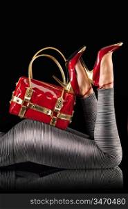 Red handbag and high-heeled shoes on female butts.