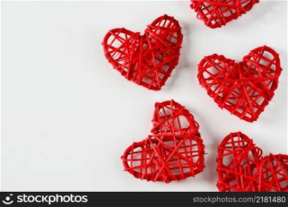 Red handmade hearts made of twigs on a white background. A lot of red hearts from twigs of vines on a white background. Background from heart for design for Valentine&rsquo;s day, place for text.. Red handmade hearts made of twigs on a white background