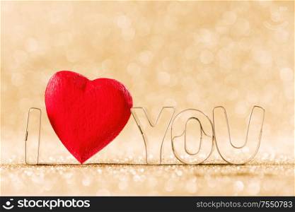 Red handmade wooden heart and words I love you on golden bright glitter lights bokeh background. Wooden heart and I love you