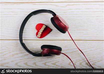 Red headphones and music written red heart on a wooden background