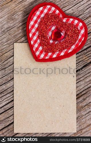 Red heart and paper piece on a wood background