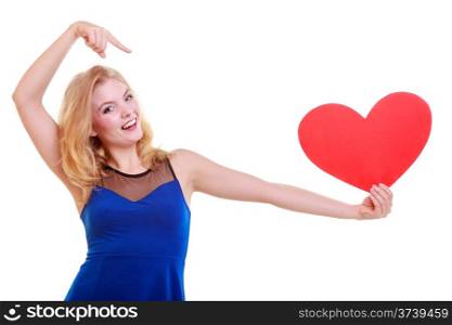Red heart card. Love symbol. Beautiful woman hold Valentine day symbol pointing. Cute blonde girl in blue dress expressing tender feelings. Isolated studio shot