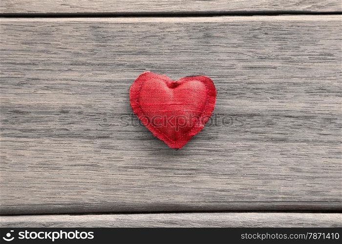 Red heart handmade craft from silk cloth place in the middle of wood background, valentine&rsquo;s day symbol