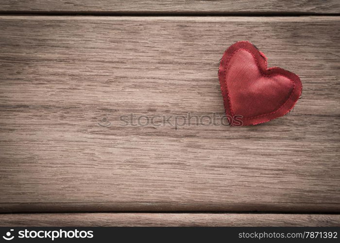 Red heart handmade craft from silk cloth place on right side of wood background with space for text, retro style with vignette, valentine&rsquo;s day symbol