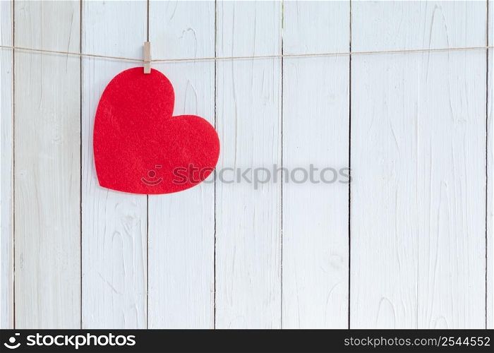 Red heart hanging on white wood background with copy space.