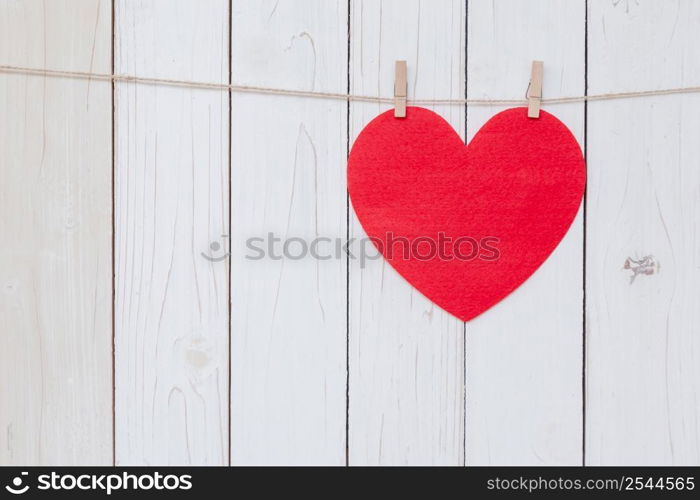 Red heart hanging on white wood background with copy space.