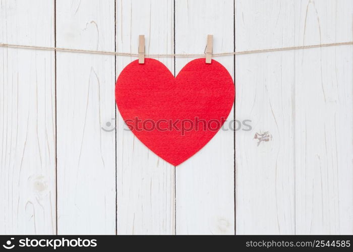 Red heart hanging on white wood background with copy space.