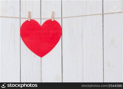 Red heart hanging on white wood background with copy space.