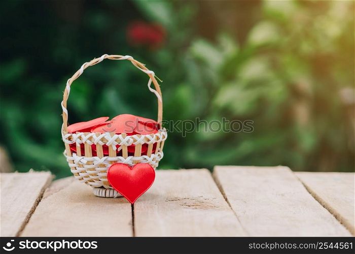 Red heart in basket on wooden table for valentine day and love concept with copy space.