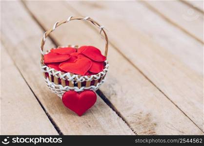 Red heart in basket on wooden table for valentine day and love concept with copy space.