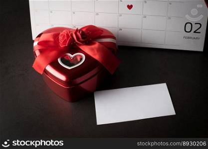 Red Heart in February 14 on the calendar with Heart shaped gift box and blank note card,  Valentine’s day concept.