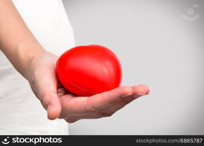 Red heart in hand on grey background