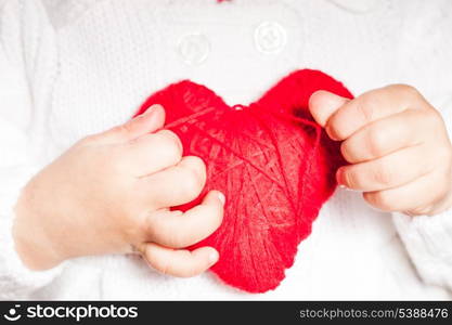 Red heart in hands of little kid in white blouse