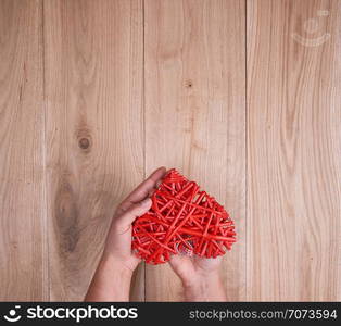 red heart in human hand on yellow wooden background of oak planks, copy space