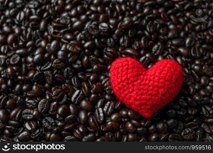 red heart on a lot of roasted coffee beans background. Strong black espresso, Grains of coffee background, texture