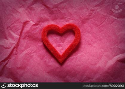 Red heart on pink paper.From above