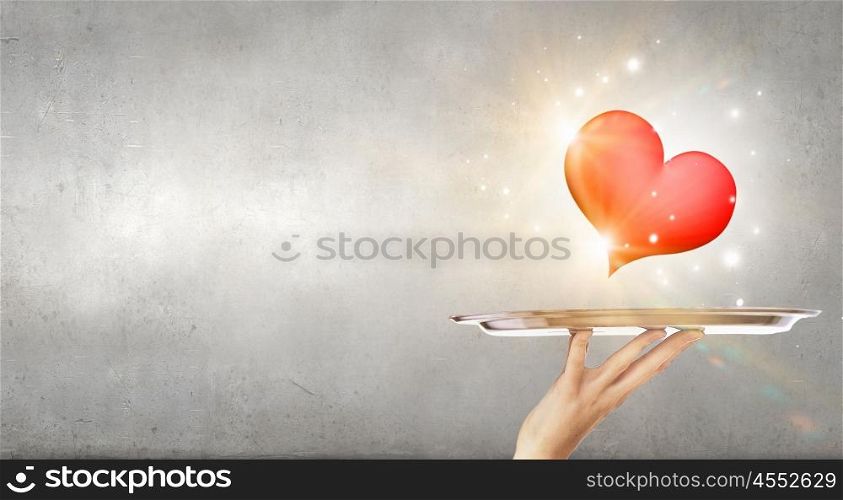 Red heart on tray. Human hand holding tray with red heart on it