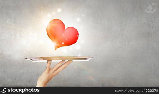 Red heart on tray. Human hand holding tray with red heart on it